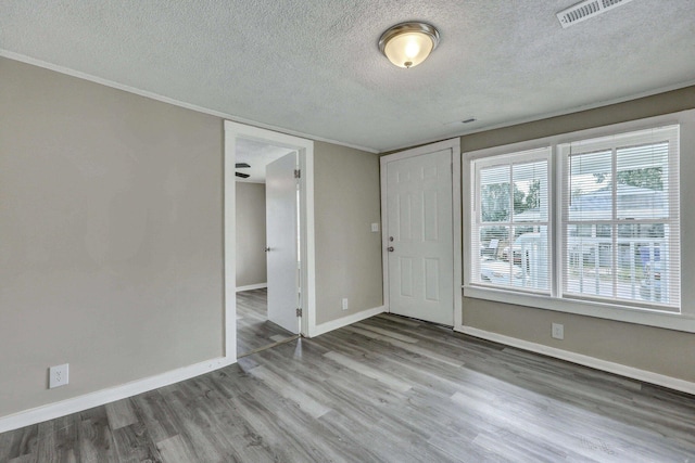 spare room with a textured ceiling and light hardwood / wood-style floors