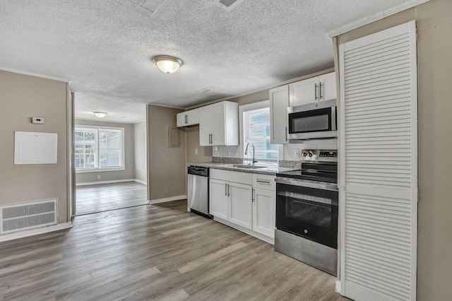 kitchen with stainless steel appliances, white cabinetry, sink, and light wood-type flooring