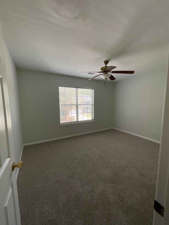 spare room with dark colored carpet and ceiling fan