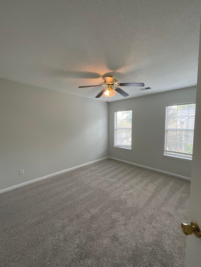 empty room featuring ceiling fan, a textured ceiling, and carpet