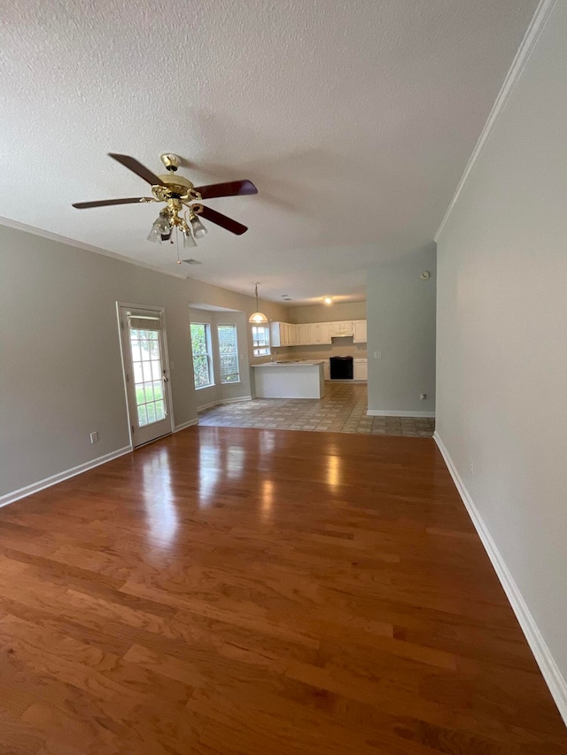 unfurnished living room featuring ceiling fan, hardwood / wood-style flooring, and a textured ceiling