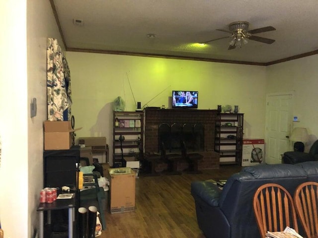 living room featuring hardwood / wood-style flooring, ornamental molding, ceiling fan, and a fireplace