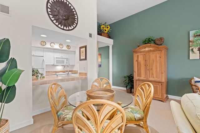 dining space featuring light colored carpet, visible vents, and baseboards