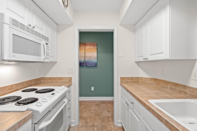 kitchen with white appliances, baseboards, a sink, light countertops, and white cabinetry