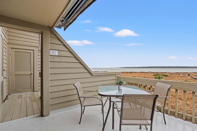 balcony with outdoor dining space and a water view