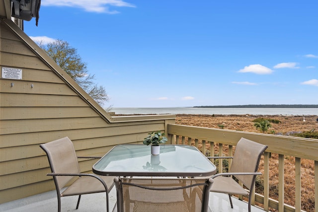 balcony with outdoor dining area and a water view