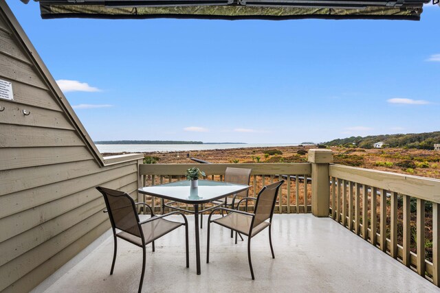 balcony featuring outdoor dining area and a water view