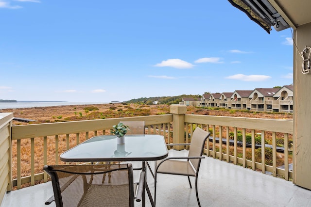 balcony with outdoor dining space and a water view