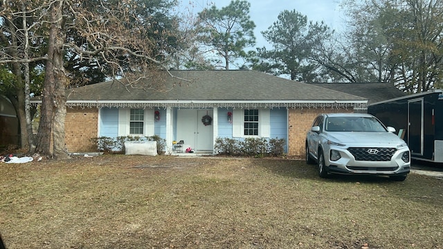 ranch-style home featuring brick siding, a front lawn, and a shingled roof