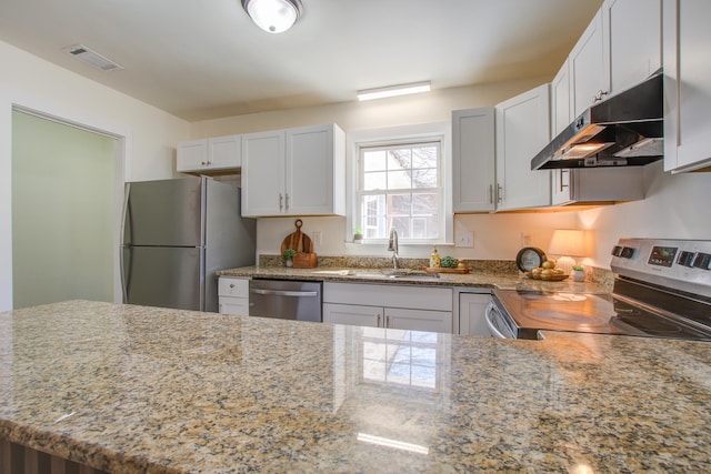 kitchen featuring light stone counters, under cabinet range hood, a sink, visible vents, and appliances with stainless steel finishes