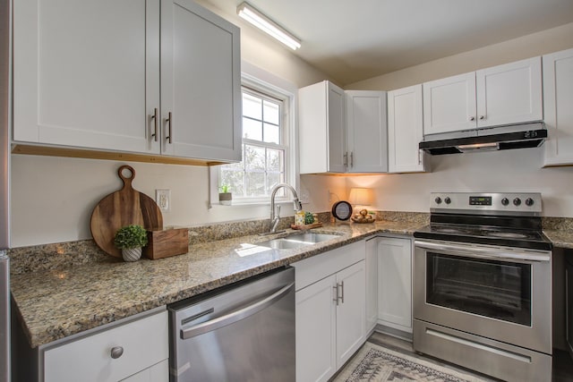 kitchen with light stone counters, under cabinet range hood, a sink, white cabinets, and appliances with stainless steel finishes