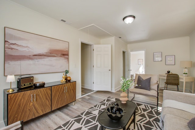 living room featuring attic access, light wood-type flooring, visible vents, and baseboards