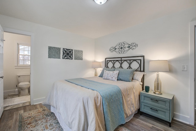 bedroom with dark wood-style floors, ensuite bath, and baseboards