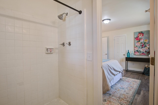 ensuite bathroom with a tile shower, ensuite bath, and wood finished floors