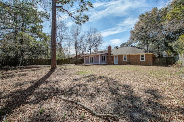 exterior space with brick siding, fence, and a chimney