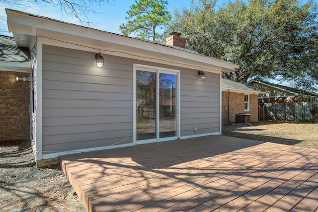 back of house featuring a deck, central AC, brick siding, fence, and a chimney