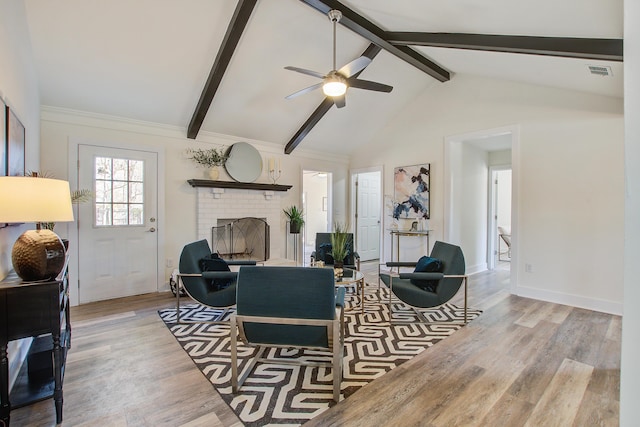 living area with a brick fireplace, baseboards, visible vents, beamed ceiling, and light wood-style floors