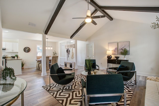 living room with baseboards, visible vents, a ceiling fan, light wood-style flooring, and beam ceiling