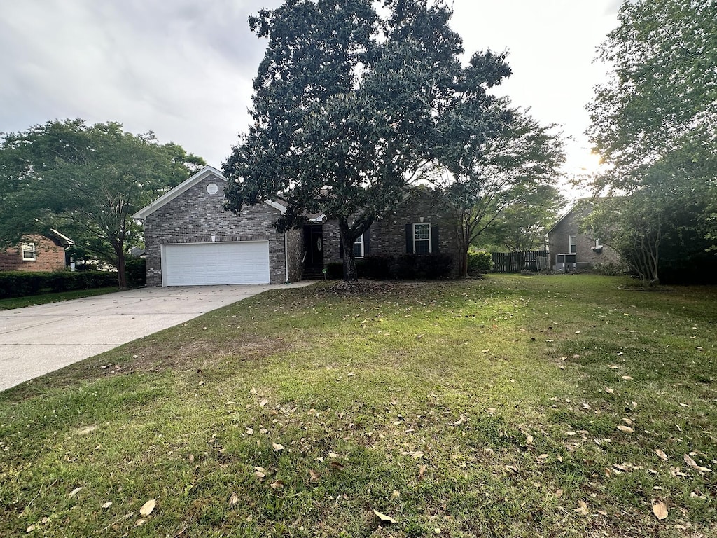 view of property hidden behind natural elements with a front lawn, driveway, brick siding, and a garage