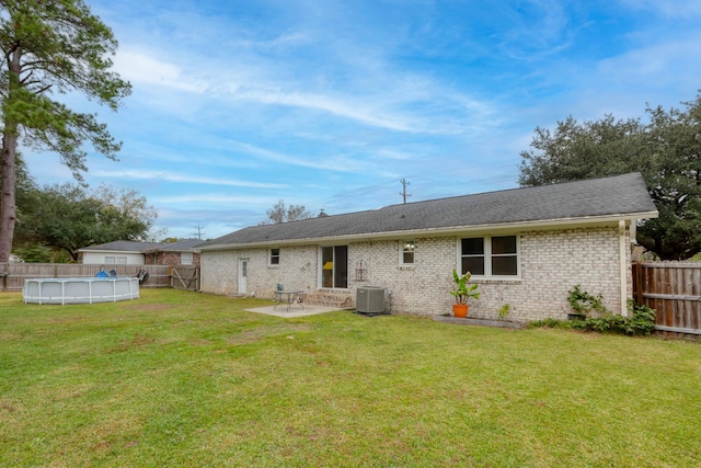 rear view of house featuring a fenced in pool, cooling unit, a patio area, and a lawn