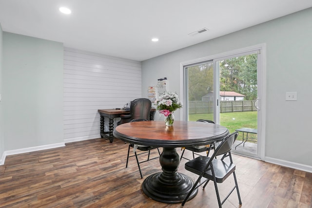 dining room with wood walls and dark wood-type flooring