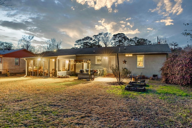 back house at dusk with a sunroom and a patio