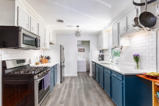 kitchen featuring stainless steel appliances, sink, washer / clothes dryer, white cabinets, and blue cabinetry