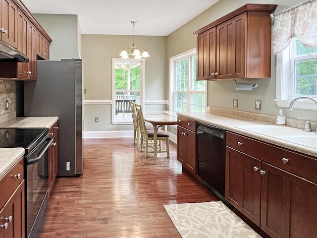 1514 Reevesville Rd, Bowman, SC 29018 - kitchen with black appliances, dark wood-type flooring, light countertops, a chandelier, and under cabinet range hood