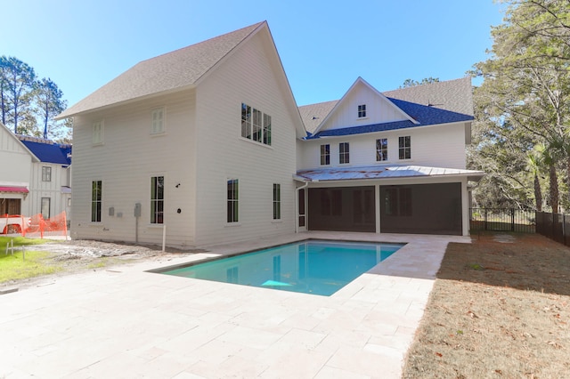 rear view of house with a sunroom, a patio area, and a fenced in pool