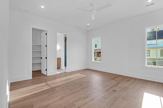 unfurnished bedroom featuring ceiling fan, a walk in closet, multiple windows, and a closet