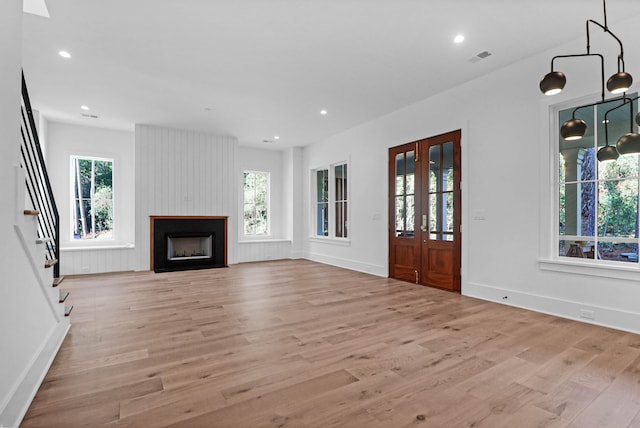 unfurnished living room with a fireplace, a wealth of natural light, and light hardwood / wood-style flooring