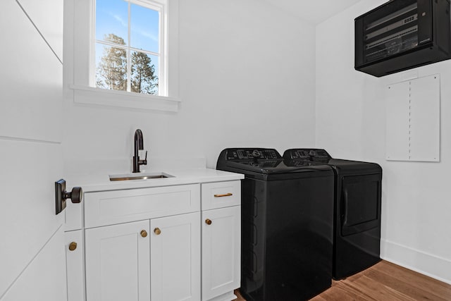 washroom featuring light hardwood / wood-style flooring, cabinets, sink, and washing machine and clothes dryer