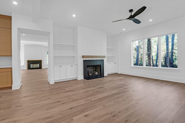 unfurnished living room with ceiling fan, light hardwood / wood-style floors, and built in features