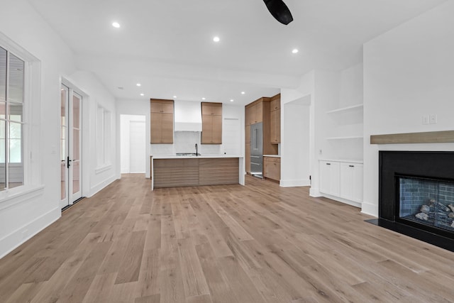 unfurnished living room featuring built in features, light hardwood / wood-style flooring, and sink