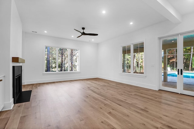 unfurnished living room with beamed ceiling, french doors, light hardwood / wood-style flooring, and ceiling fan