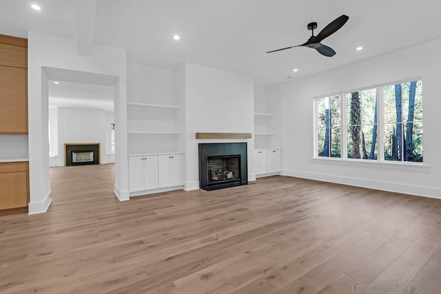 unfurnished living room featuring light hardwood / wood-style floors, built in features, and ceiling fan