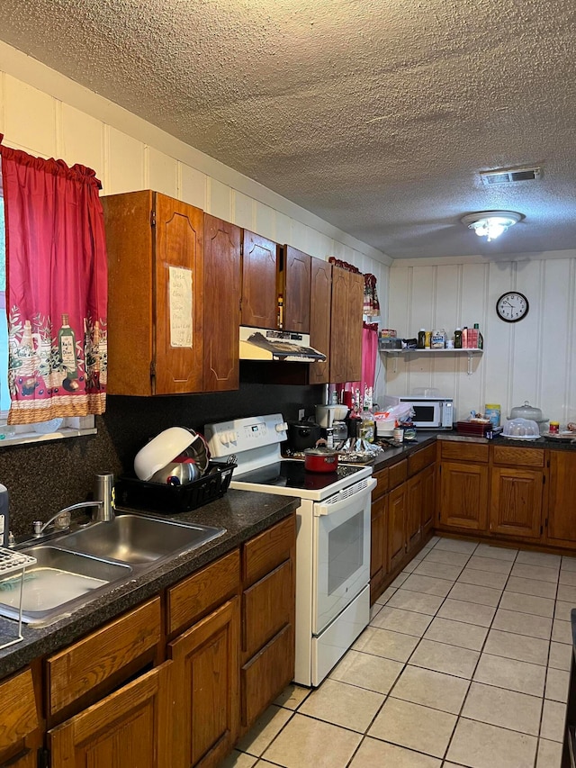 kitchen featuring sink, white appliances, light tile patterned floors, and a textured ceiling