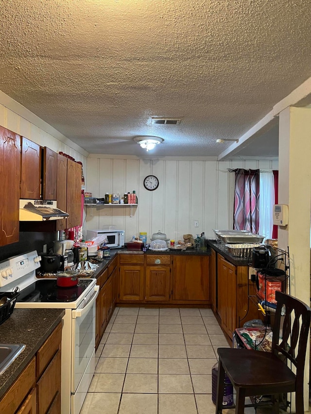 kitchen with light tile patterned floors, sink, white appliances, and a textured ceiling