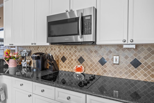 kitchen with white cabinetry, stainless steel microwave, and black electric stovetop