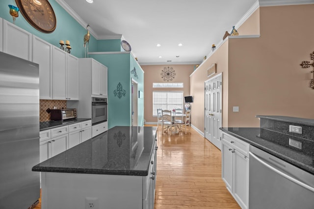 kitchen with light wood finished floors, backsplash, white cabinetry, and stainless steel appliances