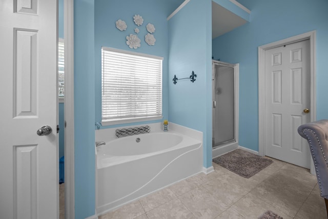 bathroom with a shower stall, a garden tub, baseboards, and tile patterned floors