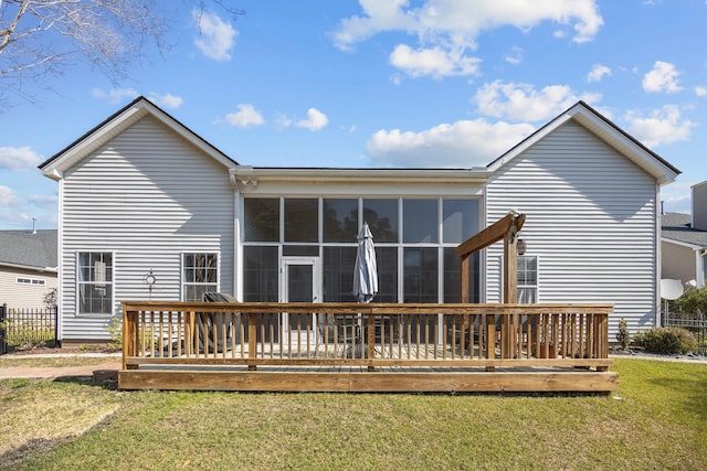 back of house featuring a wooden deck, a yard, and a sunroom