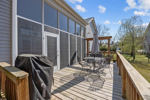 wooden terrace featuring outdoor dining space, fence, and grilling area