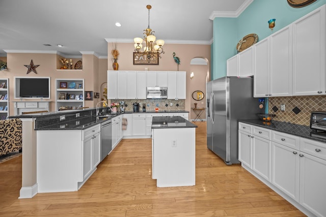 kitchen with ornamental molding, stainless steel appliances, white cabinetry, a notable chandelier, and a center island