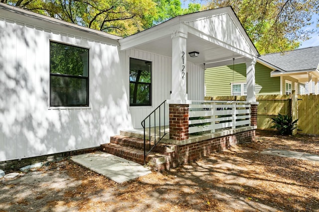 property entrance with a porch and fence