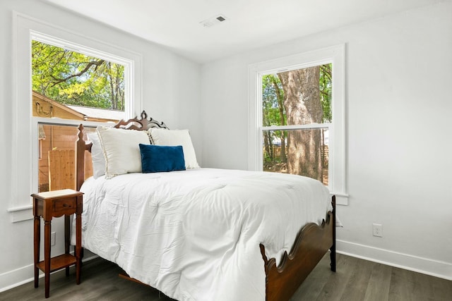 bedroom with visible vents, baseboards, multiple windows, and wood finished floors