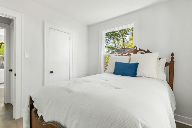 bedroom with multiple windows, baseboards, and wood finished floors