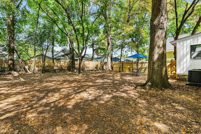 view of yard featuring central AC unit and fence