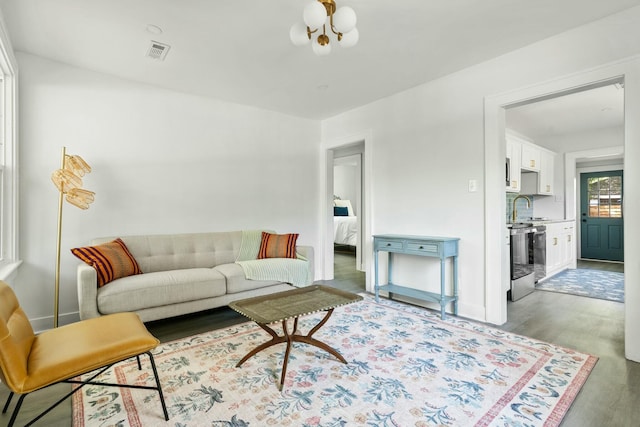 living room with a notable chandelier, visible vents, and wood finished floors