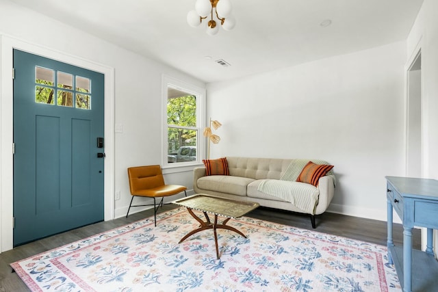 living room featuring visible vents, baseboards, a chandelier, and wood finished floors